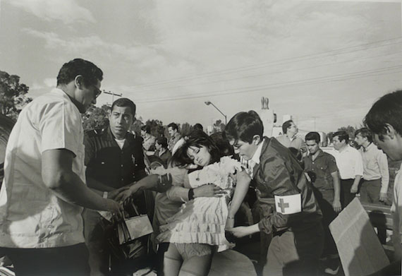 A woman being helped by medics on the road.